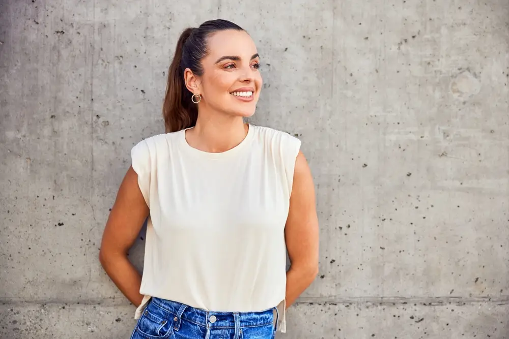 Smiling woman leaning against a concrete wall