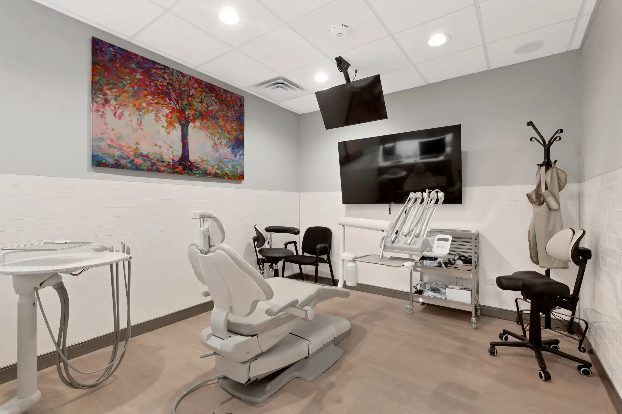Treatment room with dental chair, ceiling TV and a colourful painting