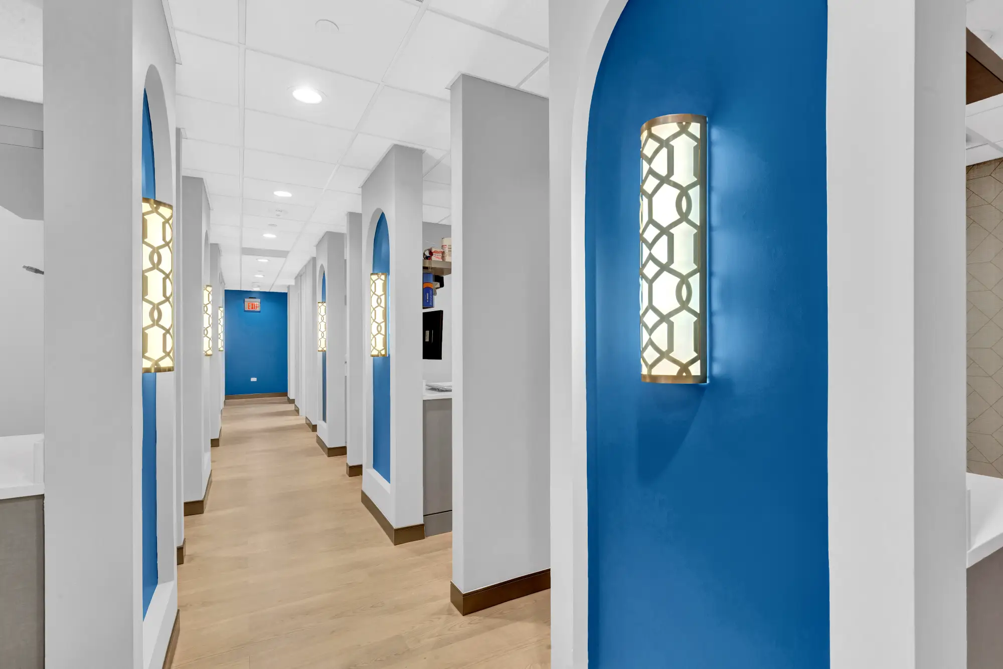 Long hallway lined with blue arched niches and sconces