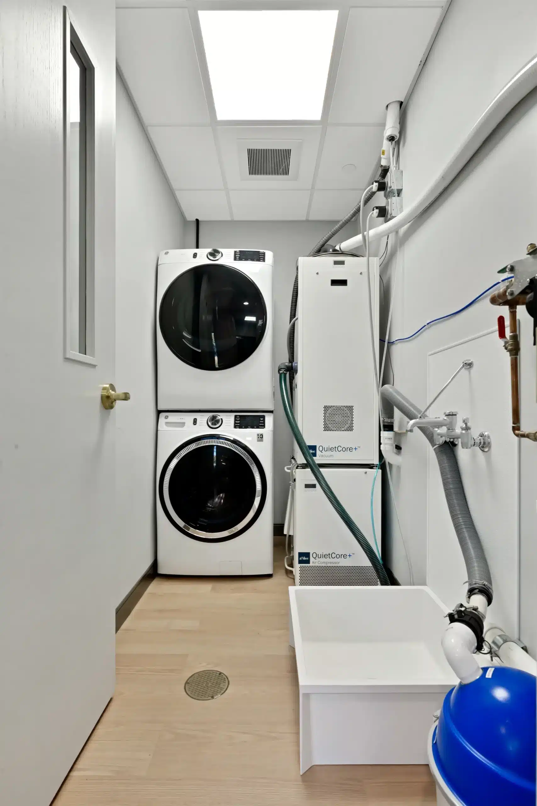 Laundry room with stacked washer, dryer and utility sink