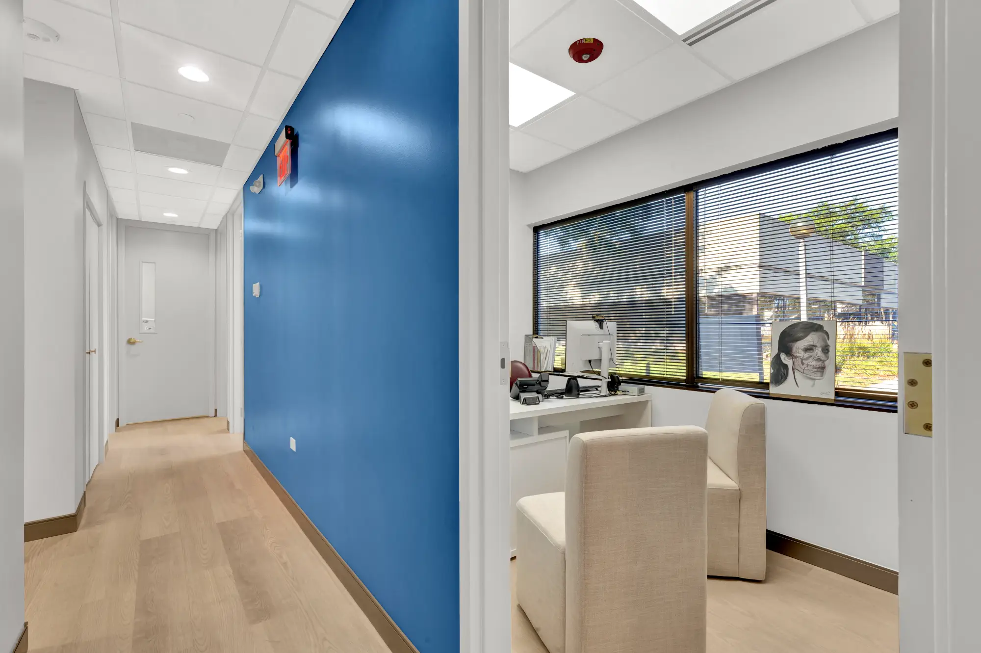 Hallway with a blue accent wall leading to an office