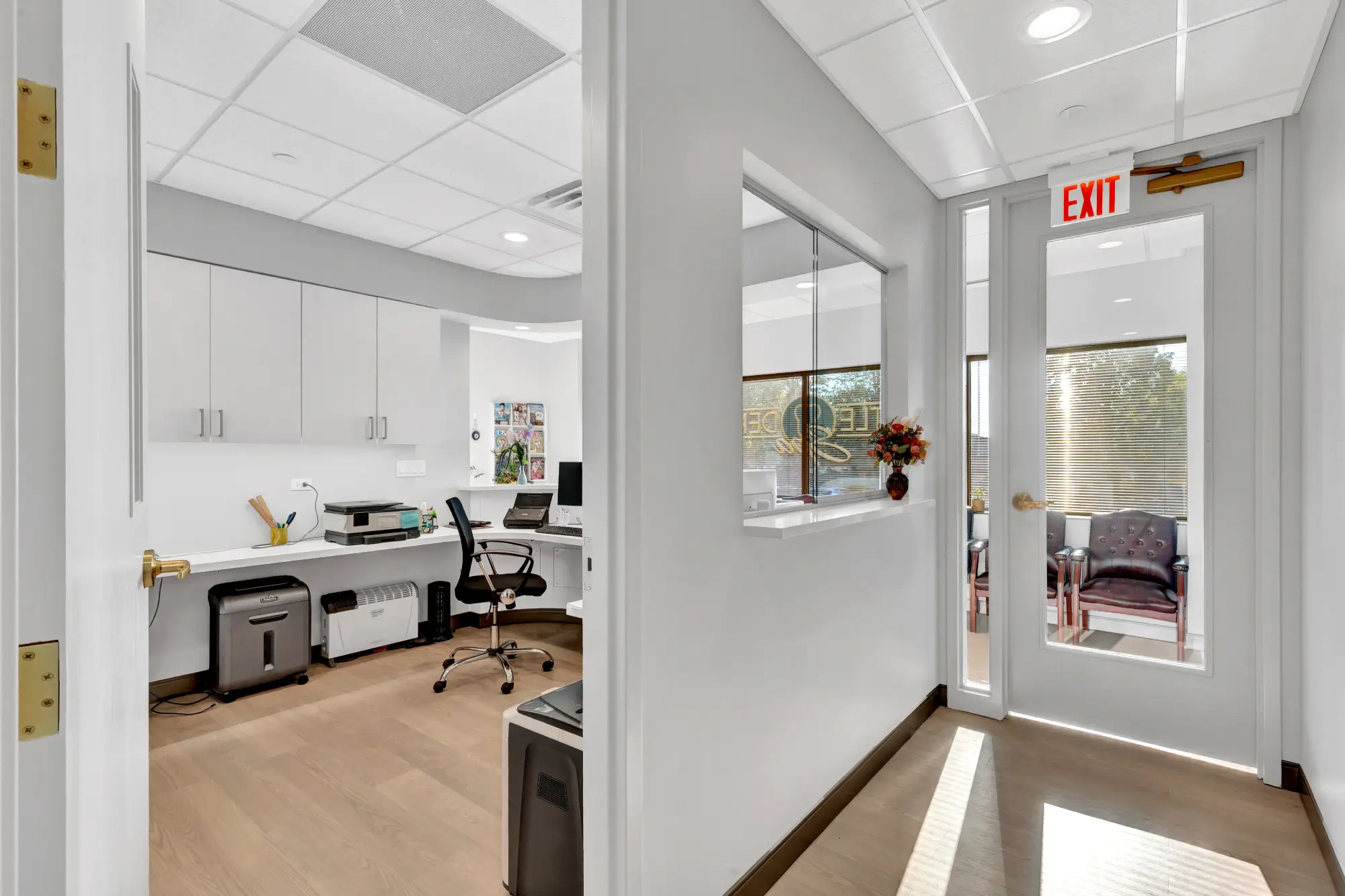 Office workspace seen through a doorway beside the exit