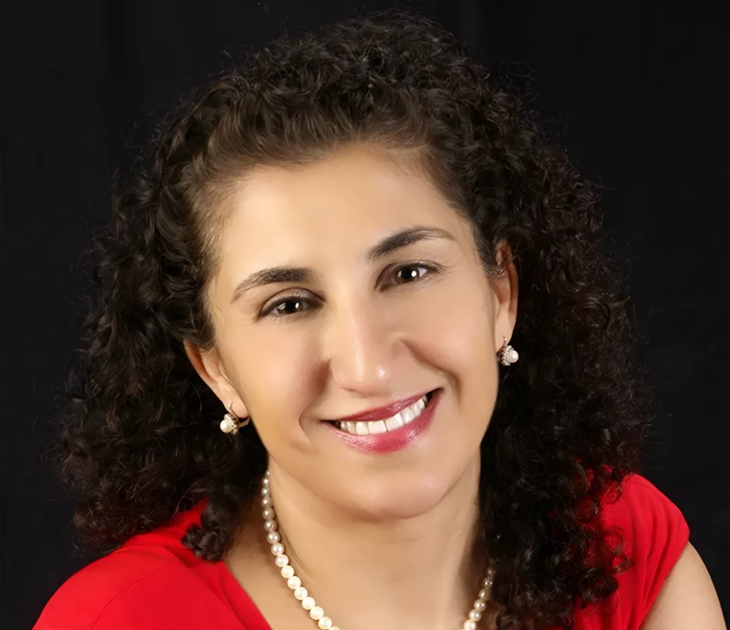 Portrait of Dr. Jacqueline Niro-Kraemer smiling, in a red top and pearl necklace