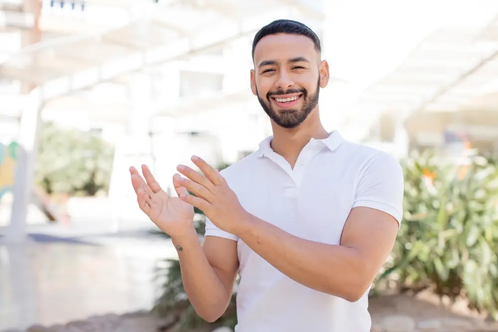 Smiling man in a white polo shirt outdoors