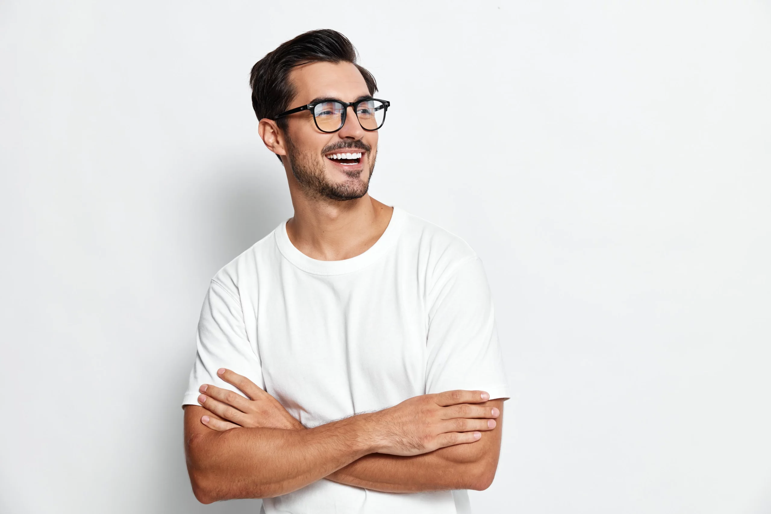Smiling man in glasses and a white T-shirt with his arms crossed