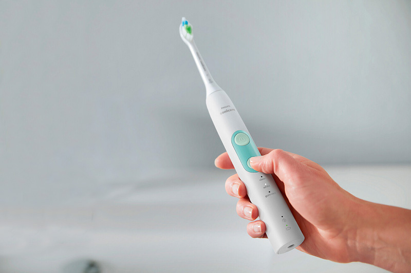 Hand holding a Philips Sonicare electric toothbrush