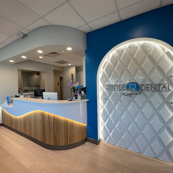 Gentle Dental Spa reception desk with the illuminated logo wall